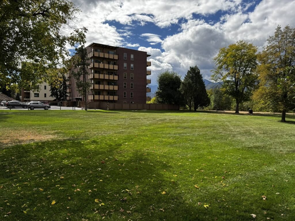 Park Manor Building 16, a brick apartment building with stacked balconies, beside a wide green lawn