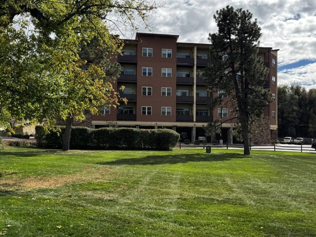 Park Manor Building 17, built in 2018, seen across a green lawn framed by pine and shade trees