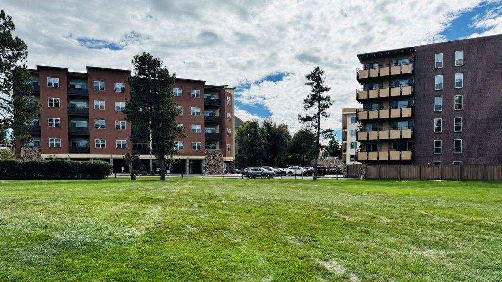 Both Park Manor apartment buildings facing a large, shared green lawn under a partly cloudy sky